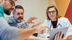 Doctor meeting with businesspeople and looking at a tablet