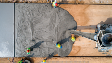 Workers lay out a layer of cement on a foundation.