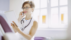 Doctor looking at tablet while on the phone