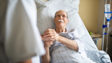 patient in hospital bed holding person's hand