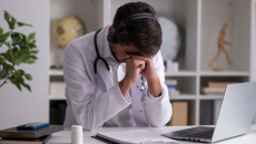 Doctor with head on hands and headset