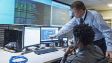 Two people examine screens with data displayed