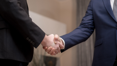 Two men in suits shake hands