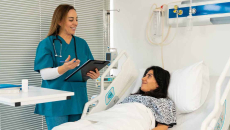 Doctor with clipboard talking to patient in hospital bed