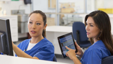Two nurses confer about clinical documentation