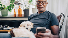 Man with his dog sitting at home having a mobile call with a care team member