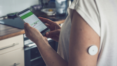 Person wearing blood glucose monitor using smartphone app