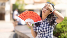 Person with fan wiping their brow