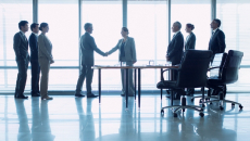 Group of businesspeople meeting with two shaking hands