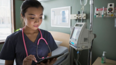 Nurse checks tablet to communicate on shift