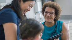 A female doctor laughs with a mother and daughter