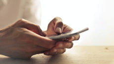 Hands on table holding a mobile phone