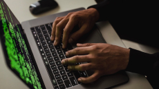 Hands are typing on a laptop with code on the screen.
