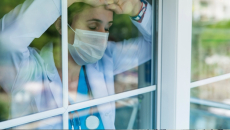 Sad doctor in mask looking out the window