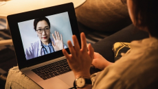 Person waving at clinician on laptop screen