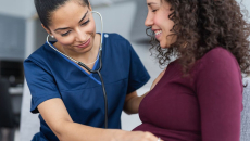 Doctor examining pregnant person with stethoscope
