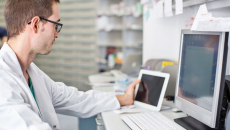 A clinician using a digital tablet and desktop computer