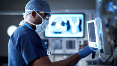 Surgeon using medical computer with x-ray in background
