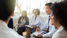 Laughing hospital administrators sitting down in a circle for a discussion