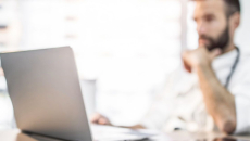 A doctor reviewing a patient file on their laptop