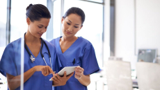 Two healthcare workers examine a tablet