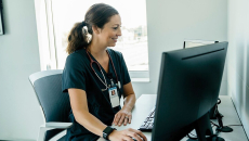 A doctor reviewing a patient's file on a desktop computer
