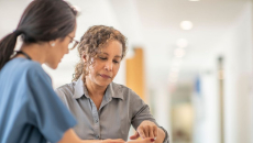 Woman in gray shirt reviews information with a clinician at the hospital