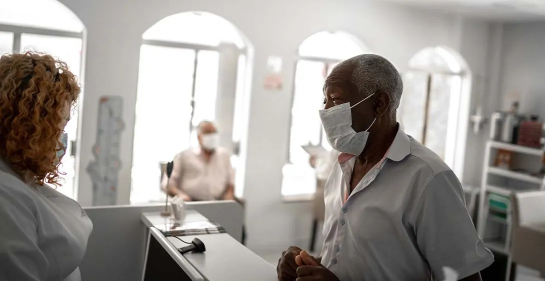 Patient in mask talking to healthcare worker in mask