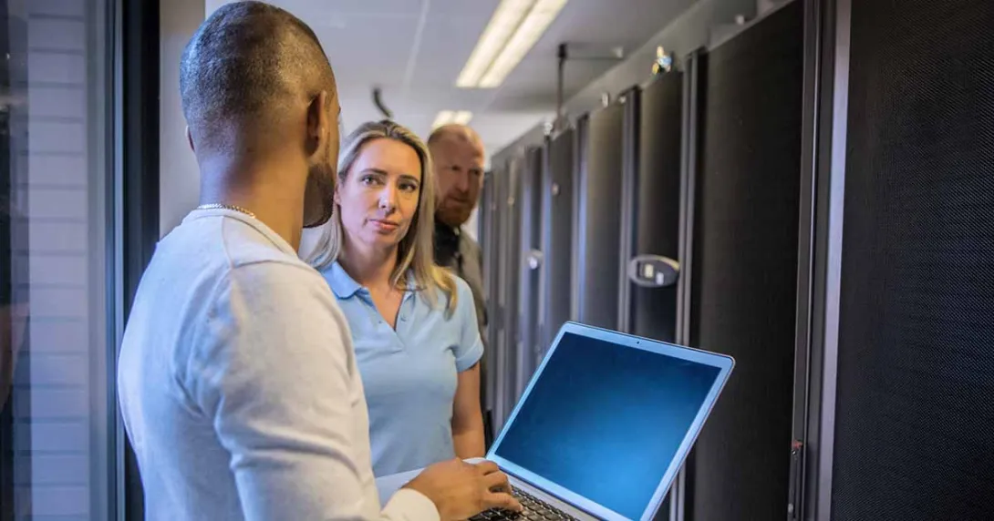 Worker with laptop talking to other IT workers