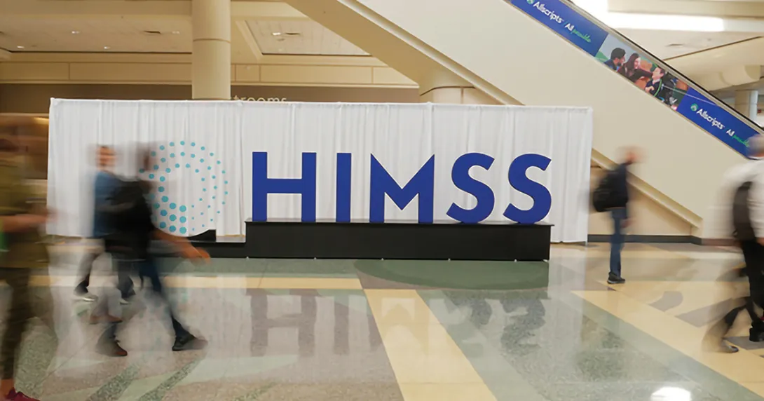 People walk by a HIMSS sign