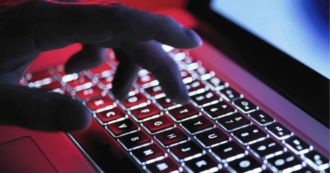 Hand on a laptop keyboard in red light
