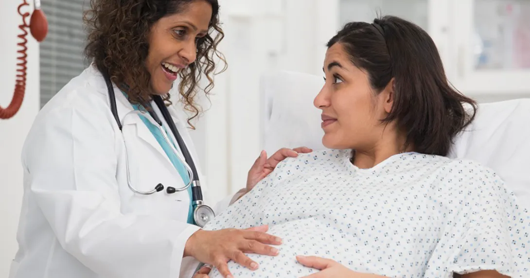 Female doctor touches a pregnant patient's belly 