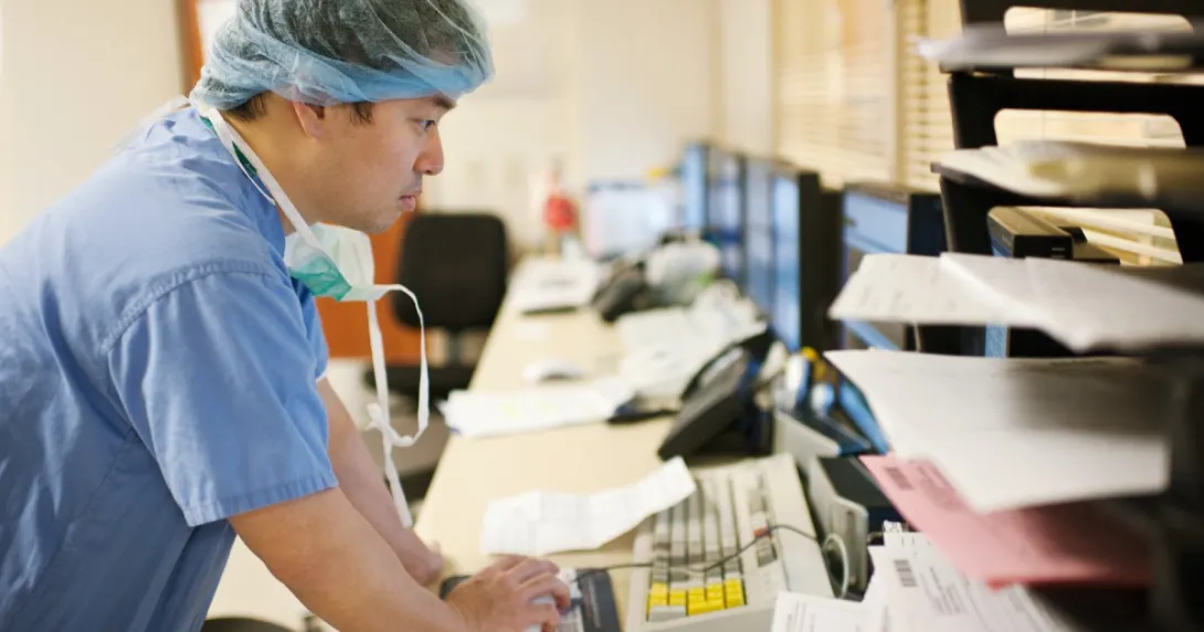 A clinician in scrubs looking at a computer
