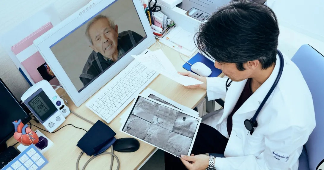 Person in lab attire looks at a scan image and talks to person via screen