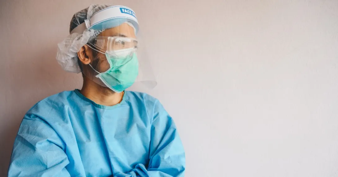 A clinician in PPE leaning against a wall