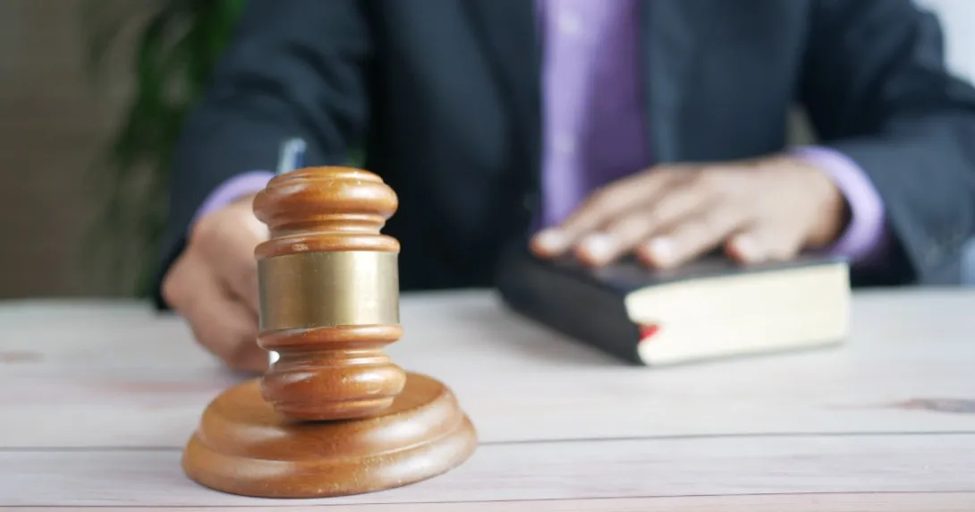 A person holding a gavel with one hand on a book