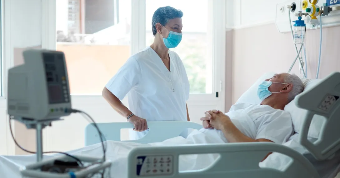 A COVID-19 patient speaks to a doctor, both in masks