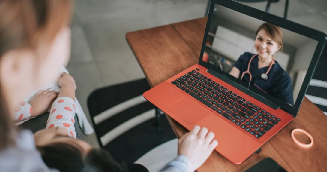 A patient with a baby on their lap speaks to a provider via telehealth