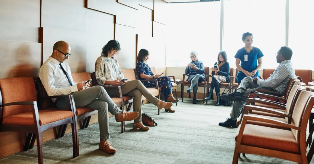 Healthcare waiting room with seated patients on their mobile phones
