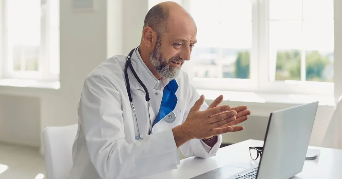 A doctor uses a laptop for an online consultation