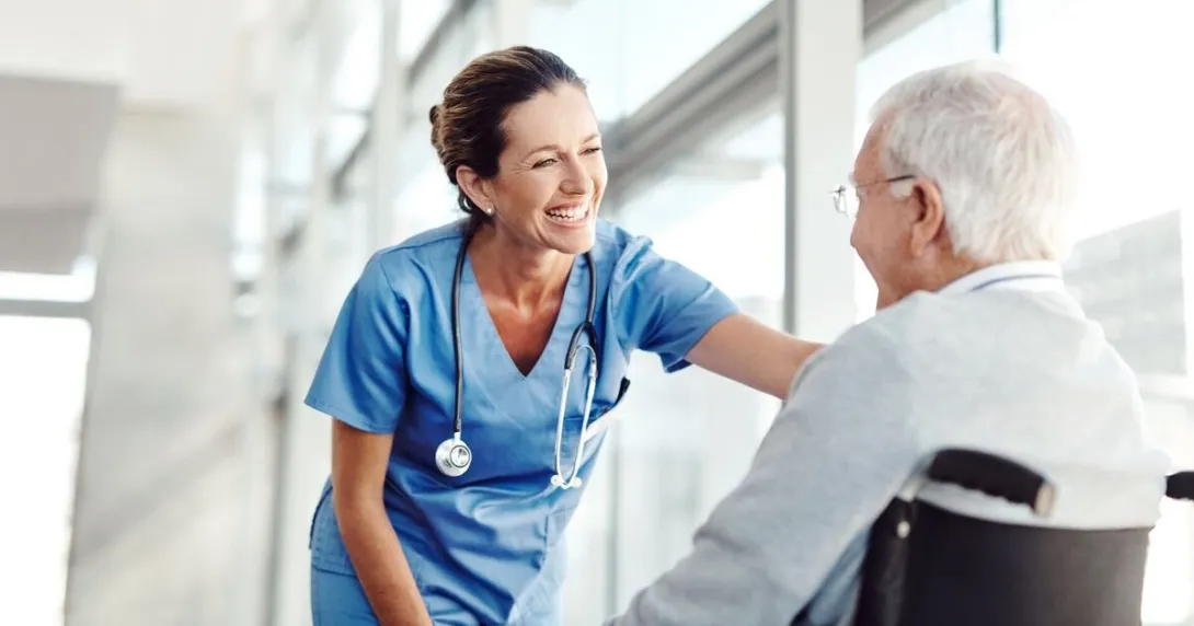 A nurse smiling at an older patient in a wheelchair