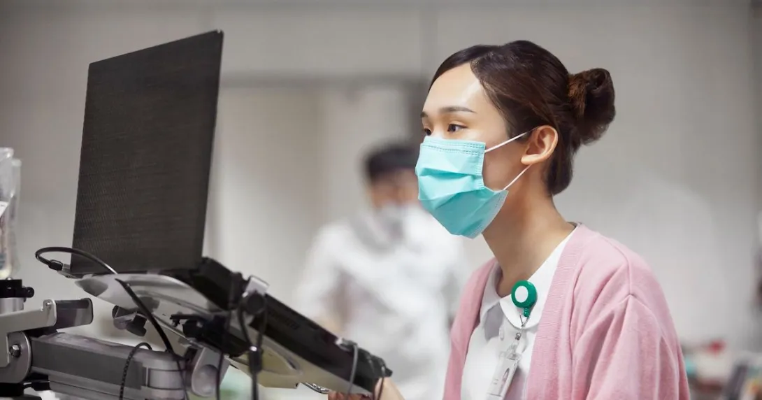 A nurse looking at a laptop dashboard of patient information