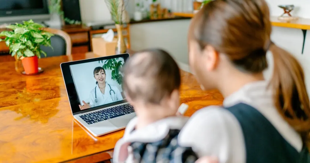A mother with her baby is in an online consultation with a doctor