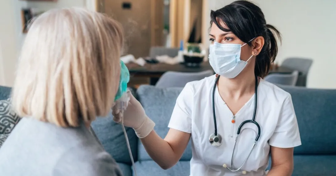 A nurse applying medical inhalation treatment through the mask of a senior patient