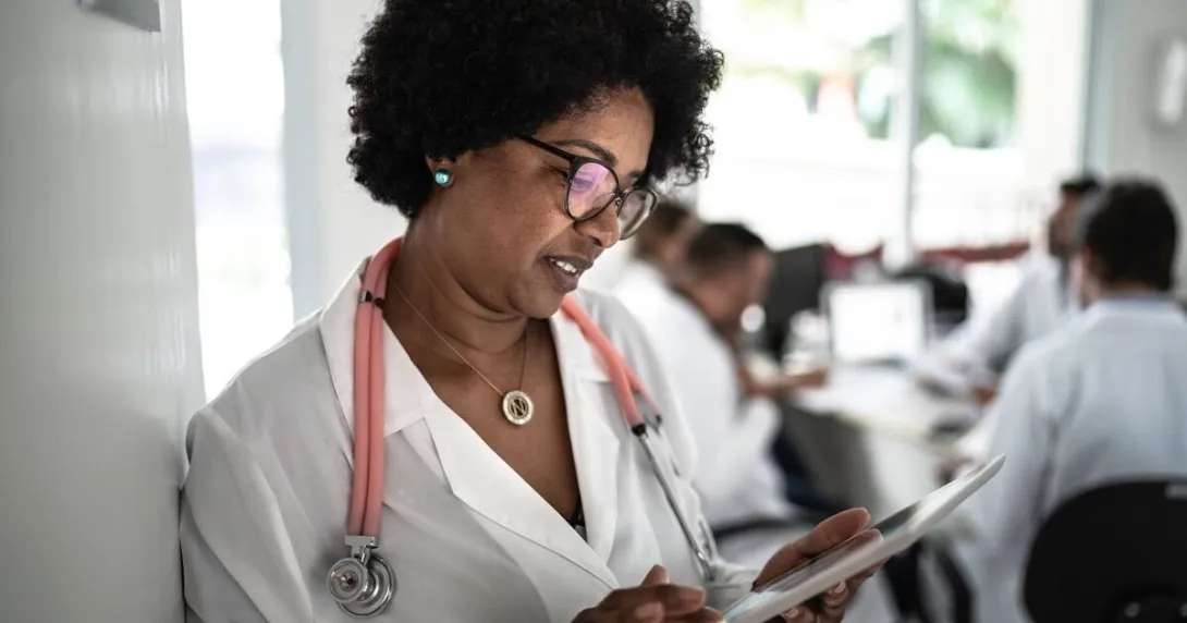 A doctor using a tablet with a doctors' conference at the background