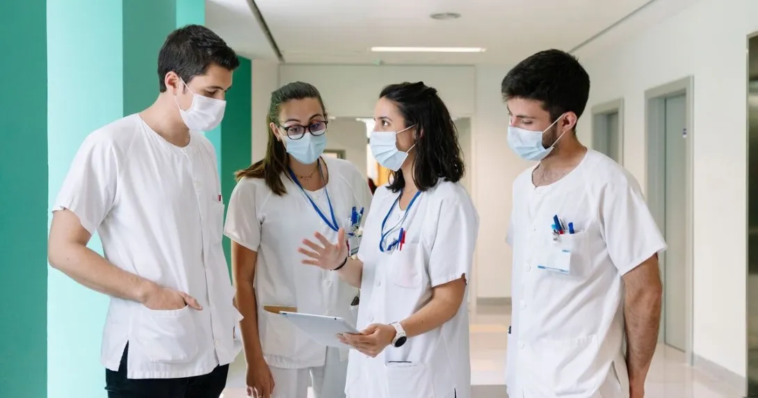 One healthcare worker talks with colleagues and references data on a tablet.