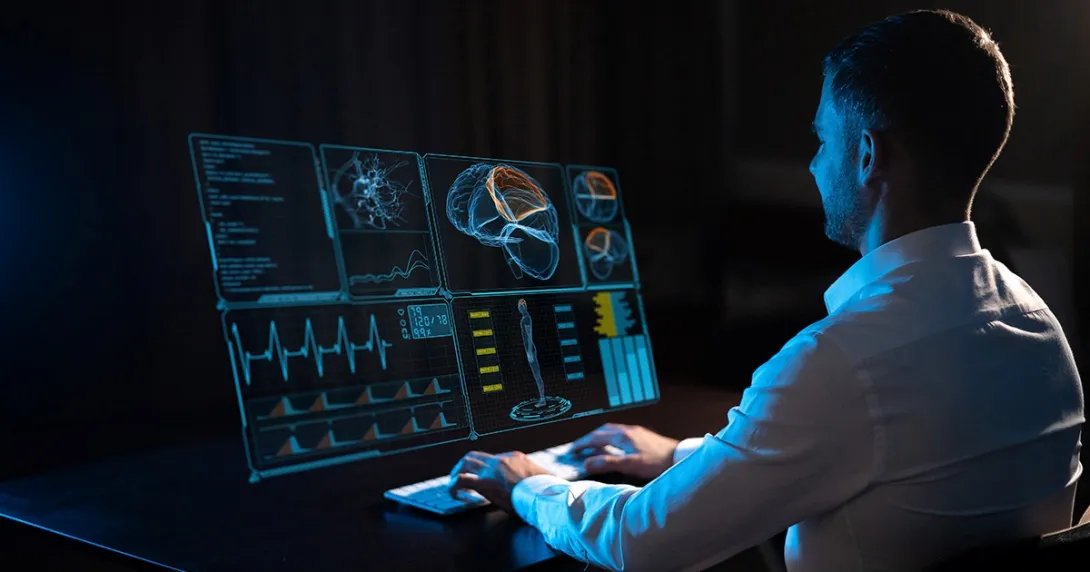 Man sitting in front of a computer screen and typing on a keyboard