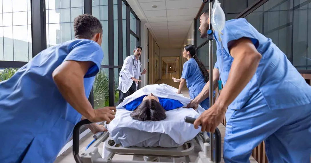 Healthcare workers rushing a patient in a gurney to the emergency room