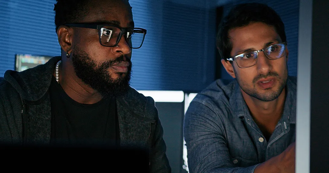 IT security staff discuss threat information in front of a network terminal 