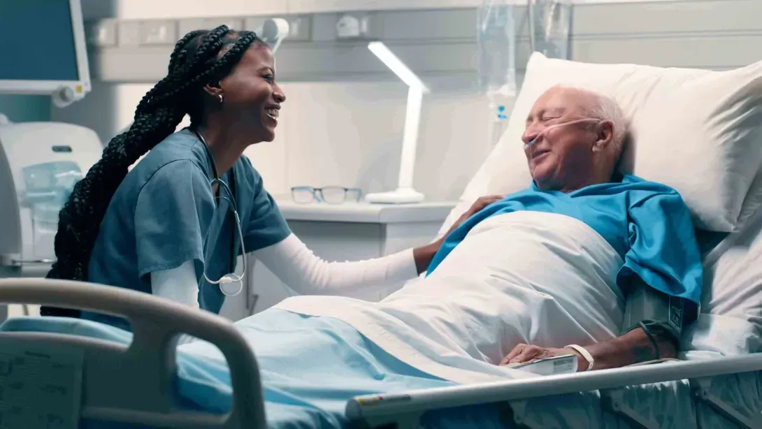 Patient in hospital bed laughing with nurse